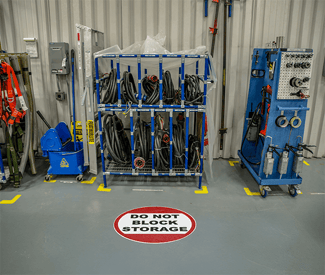 Floor sign reading "Do Not Block Storage" in front of organized hose racks.