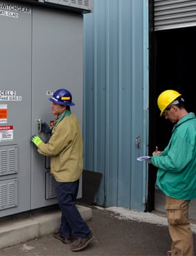 Manager and worker assess electrical equipment.