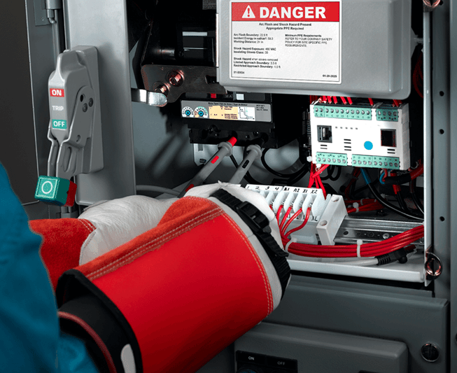 A worker in electrical safety PPE sorting wires under a Danger: Arc Flash Hazard Premium Vinyl Label