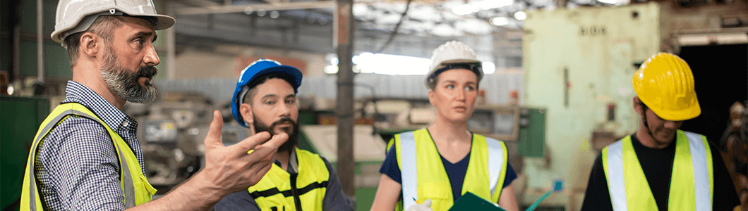 A safety manager talking to a group of employees in a factory