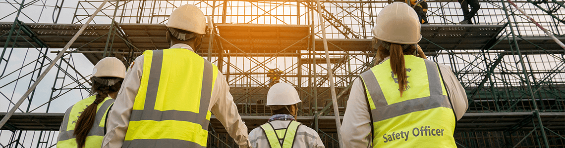 An OSHA Safety Officer and other stakeholders looking up at scaffolding at a worksite.