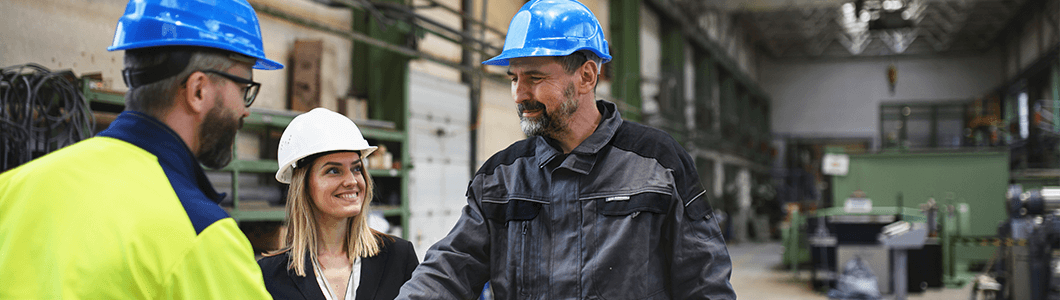 Three people wearing PPE in a factory shaking hands