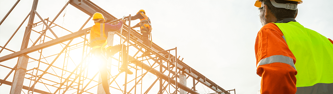 A crew of workers framing a metal structure while wearing fall safety equipment