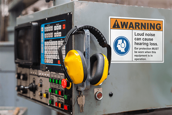 Hearing PPE hanging off a piece of equipment marked with a warning loud noises sign