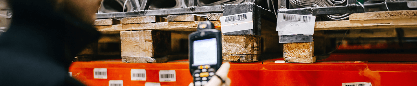 A worker using a handheld inventory scanner to scan barcode labels.