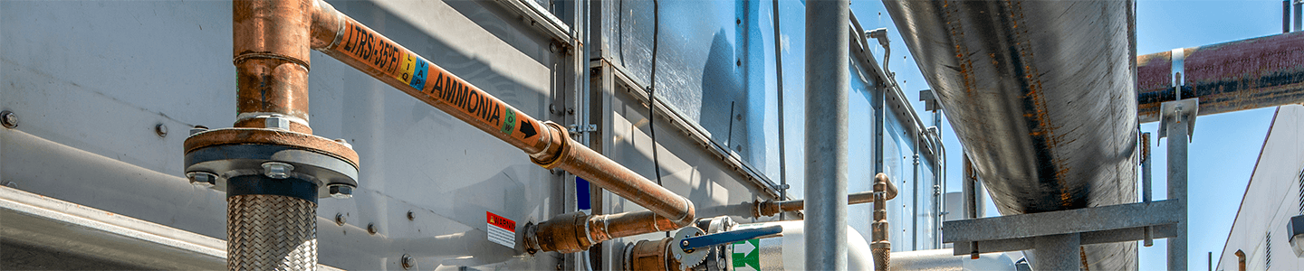Refrigeration pipe labels showing cooling water direction in mechanical room.