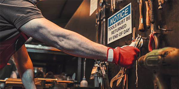 Worker in a warehouse aisle referencing shelf markers and OSHA labels for efficient material handling.