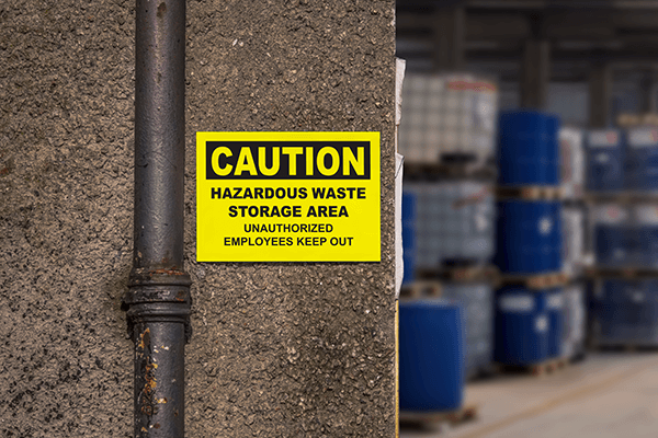 A caution sign alerting workers of entering a hazardous waste storage area.