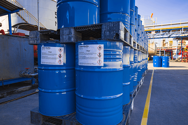 Properly labeled chemical drums with GHS hazard labels in an industrial storage area.