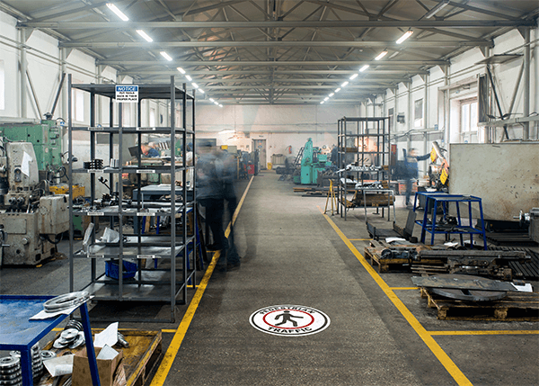 Warehouse aisle with floor sign directing foot traffic.