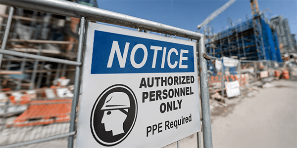 Construction safety sign reading 'Authorized Personnel Only—PPE Required' at job site entrance.