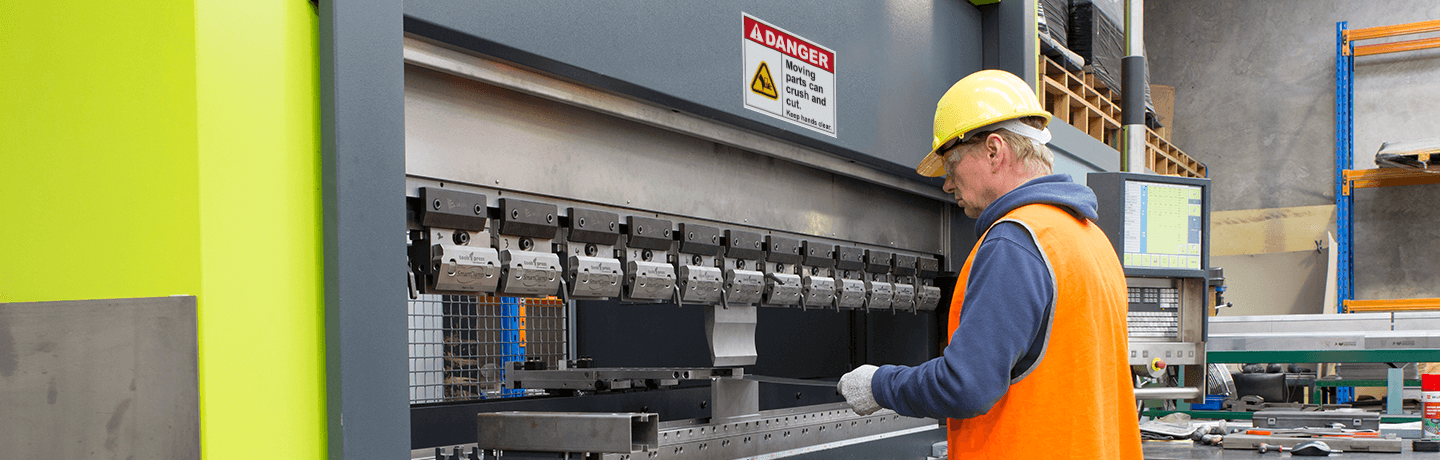 A worker operating equipment with a label that reads, 