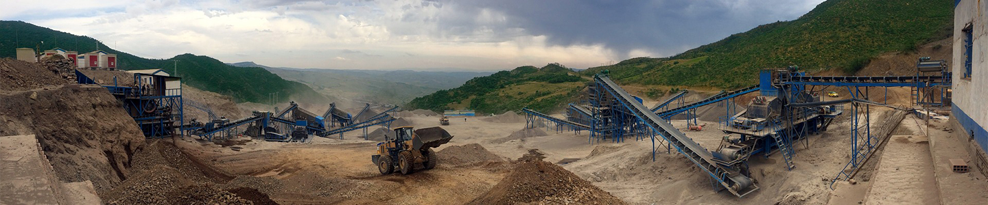 A quarry/worksite with vehicles and equipment in  action.