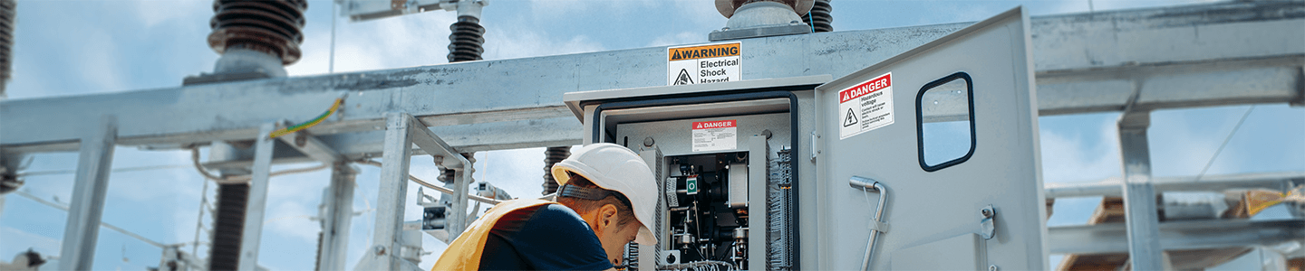 An electrician is working in a properly labeled electrical control panel on a jobsite.