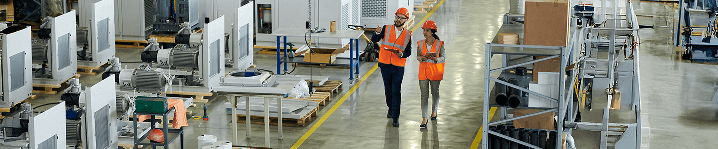 Man and woman walking down warehouse floor in safety vests