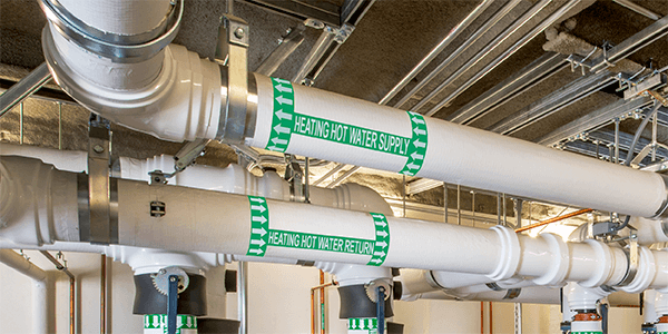 Labeled heating water pipes with clear pipe marking for direction and flow.