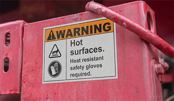 Premium vinyl label warning of hot surfaces on red industrial equipment.