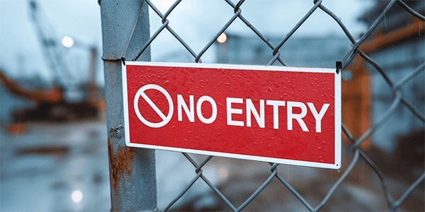 Red “No Entry” sign on a chain-link fence at a construction site.