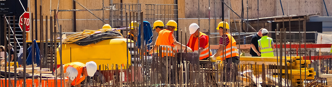 Several construction workers are working in a rebar frame on a job site.