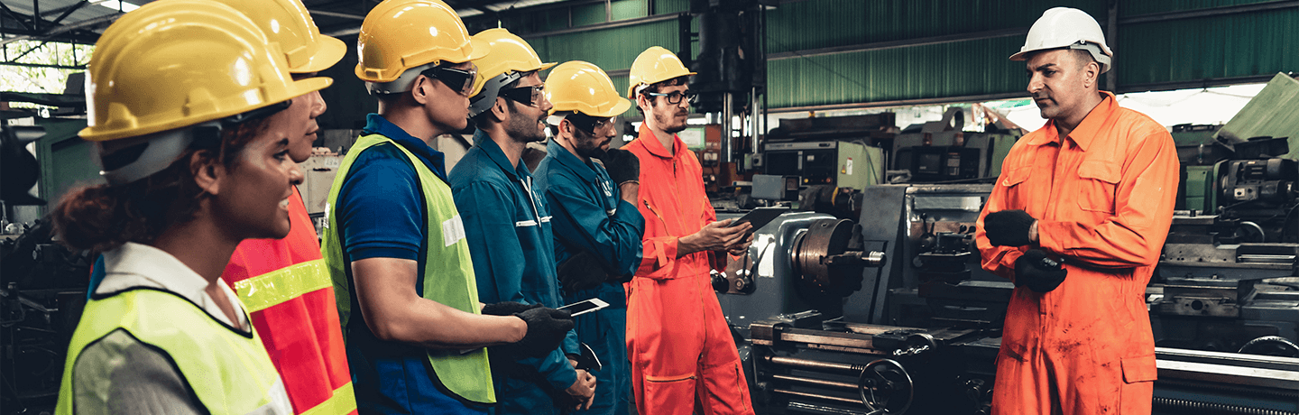 A supervisor talking to his crew in a factory setting