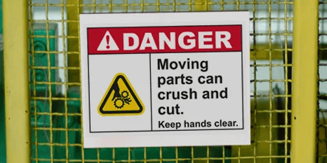 Danger label showing how workplace safety sign warns of moving parts.