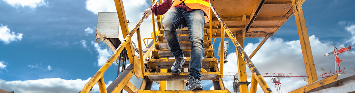 Worker walking down a large cranes stairs holding the railing.
