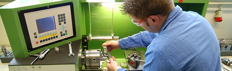 A worker uses calipers to measure the connecting rod on a lathe or other manufacturing machine.