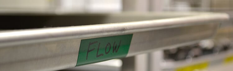 Label showing 'FLOW' on a shelf, illustrating effective warehouse management with industrial labeling solutions.