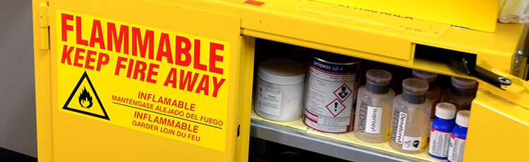 A Flammable: Keep Fire Away label affixed to a metal cabinet full of chemicals.