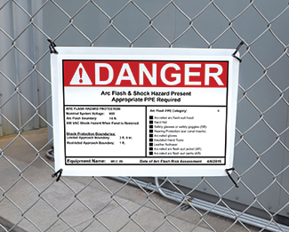 Danger arc flash and shock hazard warning sign posted on a chain-link fence.