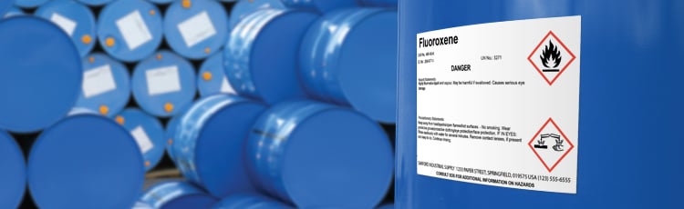 A stack of chemical drums with chemical safety labels.