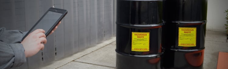 A black hazardous waste drum marked with a warning label.