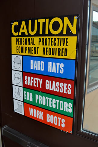Sign reminds workers to wear PPE.