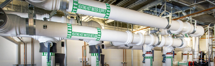 Labeled heating water pipes with clear pipe marking for direction and flow.