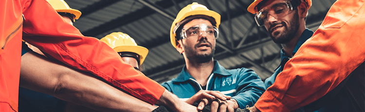 Workers in hardhat and PPE speaking to one another.