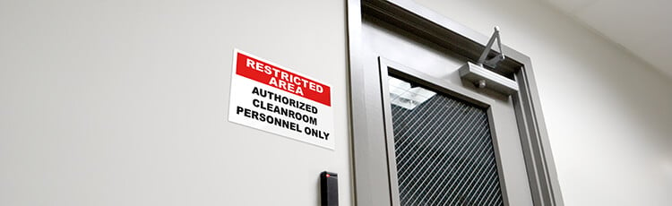 A restricted area sign is featured on the outside of a cleanroom next to the door.