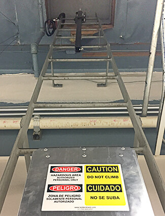 Signs warn workers of dangers on a ladder.