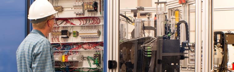 An engineer works on a circuit board/electrical panel.