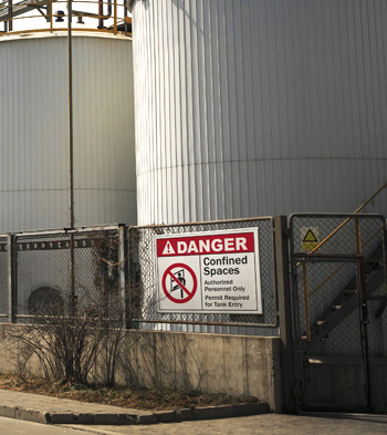 A large sign warns of storage tank dangers.
