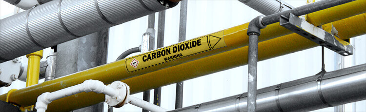 A carbon dioxide pipe marker shown on one of many industrial pipes pictured.