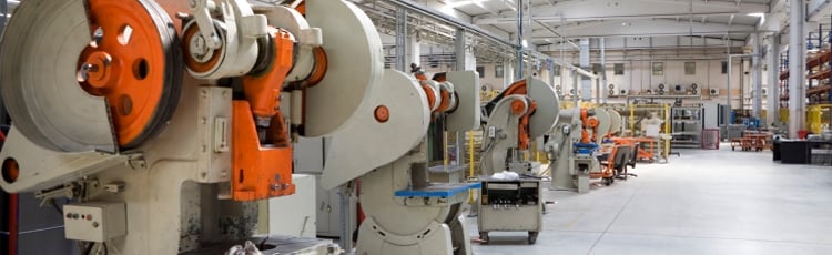 Large machines on the floor of a clean and organized manufacturing facility using Lean/Kaizen organization labeling and marking.