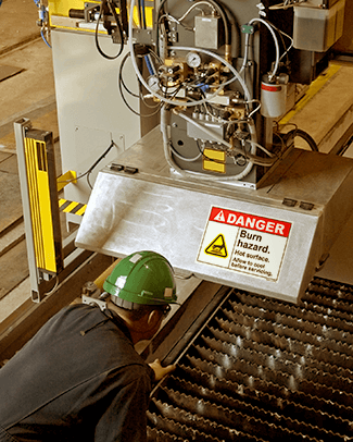 Worker inspecting machinery with safety label applied to metal equipment in an industrial facility