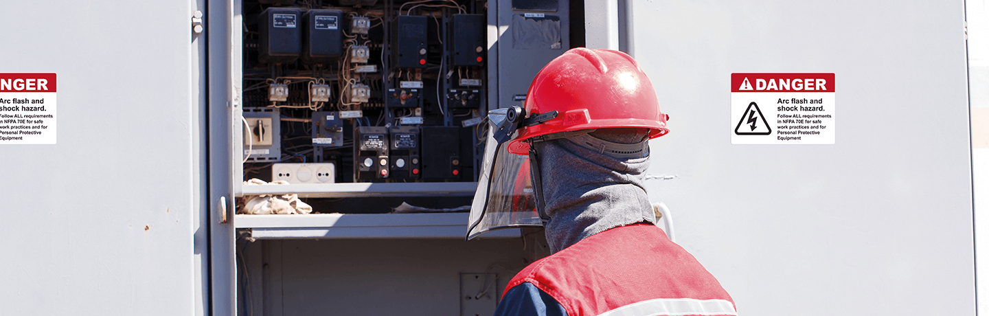 Worker in Arc Flash PPE standing in front of an open electrical panel