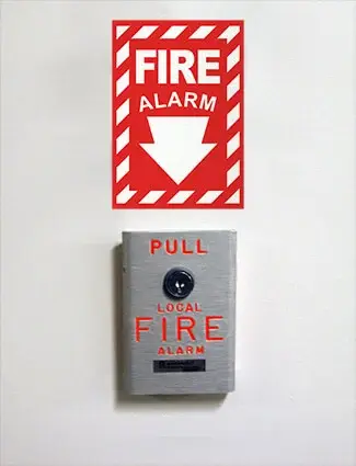 Wall-mounted fire alarm with high-visibility OSHA-approved sign directing employees to activate in case of emergency.